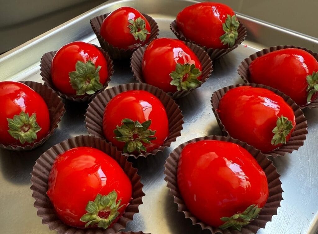 Morango do Amor com calda vermelha e brilho comestível simbolizando afeto e desejo.