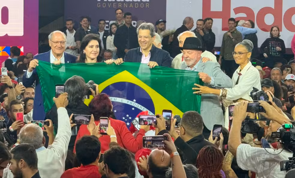 Justiça Eleitoral de SP multa Lula em R$ 15 mil por campanha antecipada TRE-SP condena o presidente por pedido de voto a Simone Tebet e Marina Silva em evento de maio O Tribunal Regional Eleitoral de São Paulo (TRE-SP) condenou o presidente Luiz Inácio Lula da Silva (PT) a pagar uma multa de R$ 15 mil por propaganda eleitoral antecipada. A decisão, do juiz Ronnie Herbert Barros Soares, acolheu parcialmente uma ação do partido Missão. O partido questionou declarações de Lula em um evento em São Paulo no dia 19 de maio de 2026, transmitido ao vivo pelo canal oficial do presidente no YouTube. No discurso, Lula afirmou: “O que vocês podem fazer com elas um dia, é dar voto para as duas, só isso. Um dia, sabe?” — referindo-se a Simone Tebet e Marina Silva, pré-candidatas ao Senado por São Paulo. O juiz considerou a expressão “dar voto para as duas” um pedido explícito de apoio eleitoral, proibido fora do período permitido. A defesa de Lula alegou que a fala tinha caráter institucional e não era pedido de voto, mas o magistrado rejeitou o argumento. A multa foi fixada acima do mínimo legal porque a conduta partiu do Presidente da República em evento oficial. O TRE-SP também determinou a exclusão do vídeo do YouTube. O pedido de multa contra Simone Tebet e Marina Silva foi julgado improcedente, por falta de provas de que elas tinham conhecimento ou participação no discurso. A Procuradoria Regional Eleitoral já havia se manifestado pela punição apenas de Lula. Geraldo Alckmin, Simone Tebet, Lula e Marina Silva durante convenção para lançar candidatura de Fernando Haddad ao Governo de São Paulo — Foto: Marcello Carvalho/g1
